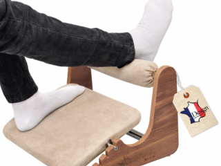Ergonomic wooden footrest with beige microfibre suede cushion and adjustable ankle support for office desk. {{brizy_dc_image_alt entityId=